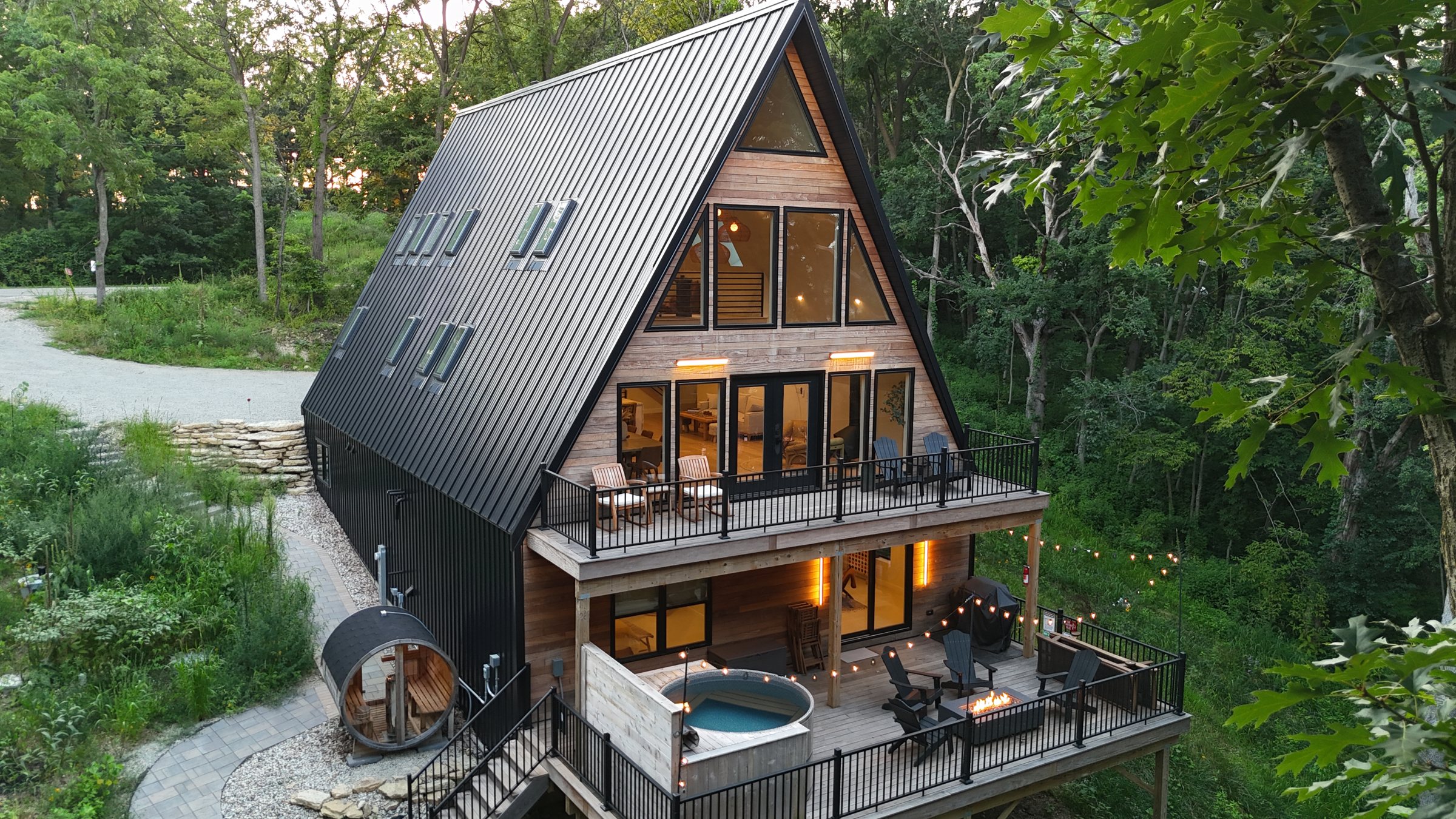The Ravines A-frame at dusk, hot tub and sauna lit below the deck